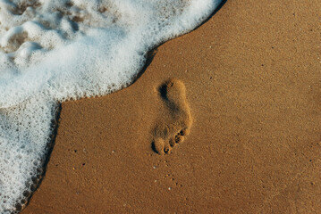 Photo of foot print on sand at the beach background