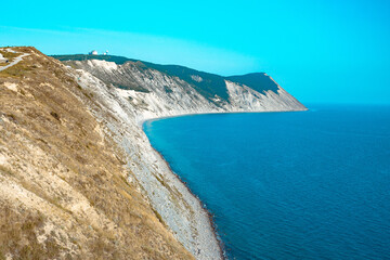 Large and beautiful mountains on the sea coast in the sunlight. Beautiful hills on the seashore with yellow grass from heat.