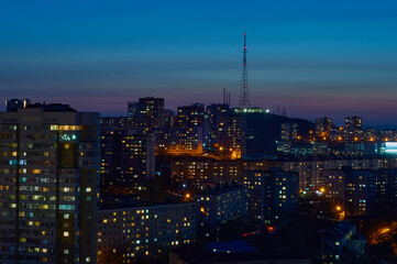 Aerial view of the night city of Vladivostok, Russia. TV tower on a hill, sea bay and mountain range.