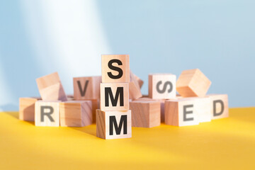 SMM written on wooden cubes, yellow background
