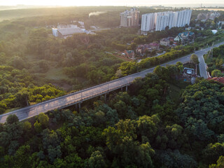 Aerial sunrise morning Derevianka street bridge across Sarzhyn Yar in Kharkiv city. Buildings with lots of greenery in fog at dawn in nice light. Drone view on Sokilnyky.