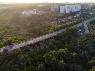 Obraz premium Aerial sunrise morning Derevianka street bridge across Sarzhyn Yar in Kharkiv city. Buildings with lots of greenery in fog at dawn in nice light. Drone view on Sokilnyky.