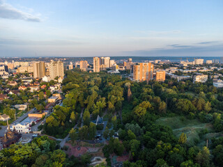 Fototapeta na wymiar Aerial morning view on green summer Kharkiv city center popular recreation park Sarzhyn Yar. Botanical garden with water spring and playground in residential area in sunrise light