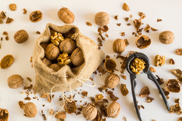 A sack of walnuts on white background with walnut cracker and copy space.Top view