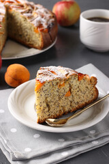 Homemade pie with poppy seeds, apricots and apples with a cup of coffee on a gray background. Vertical arrangement