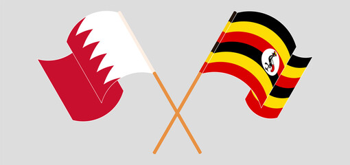 Crossed and waving flags of Bahrain and Uganda