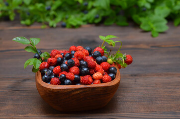ripe berries wild strawberries and blueberries in a wooden bowl close up