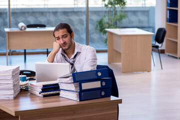 Young male employee unhappy with excessive work in the office