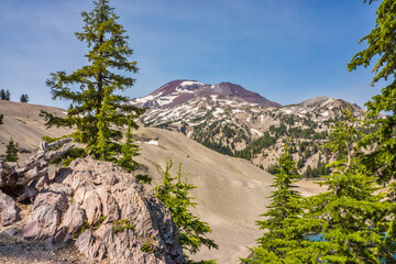 Back country campsite with a view of pumice covered moraine, fir trees on a cliff, and volcanic...