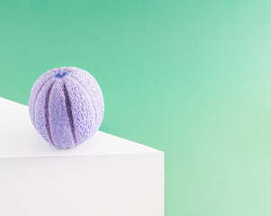 Creative layout made of purple melon on table against green pastel background. Concept art. Minimal surrealism background. Summer fruit gravity concept.
