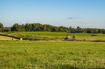 Fototapeta premium tractor with hay tedder turning hay in field