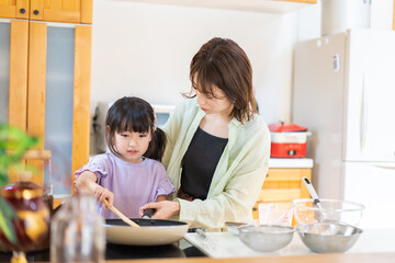 Obraz na płótnie Canvas お母さんと一緒に料理をする小さな女の子