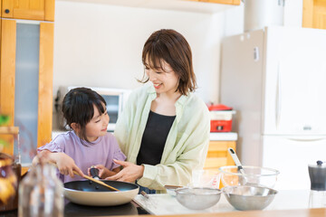 お母さんと一緒に料理をする小さな女の子