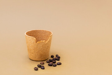 Coffee or tea cup with roasted coffee beans on beige background. Edible cups as new zero waste trend