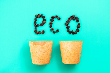 Drink It And Eat It - Edible Coffee Cups with words ECO made of coffee beans on green background, top view