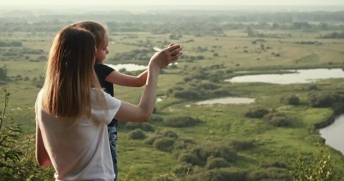 Mother and daughter on the observation deck, mother shows her hand on the woods and the river. A place to relax, walk and play sports.