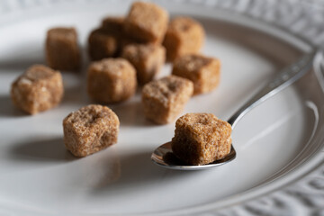 Brown cane sugar cubes on a white plate.