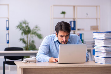 Young male employee and too much work in the office