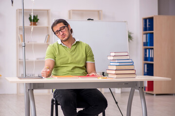 Young sick male teacher student in blood transfusion concept