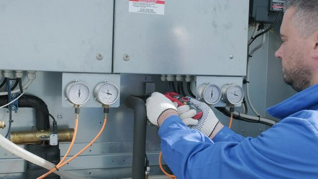 The technician checking power lines of the heat exchanger with current clamps