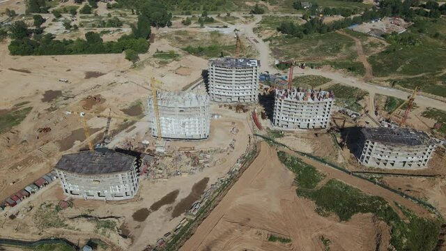 Construction of a modern city block. The concrete frames of the buildings are visible at the construction site. Construction cranes are working. Aerial photography.