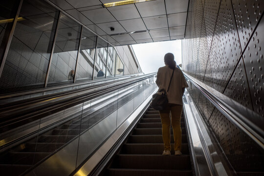 Selective focus and silhouette view at woman wear protective face mask stand on escalator at underground metro station. - Powered by Adobe