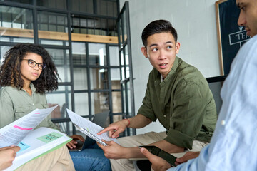 Diverse multiracial young coworkers business startup creative team people or students discussing project brainstorming ideas on meeting with Asian leader in contemporary office at training workshop.