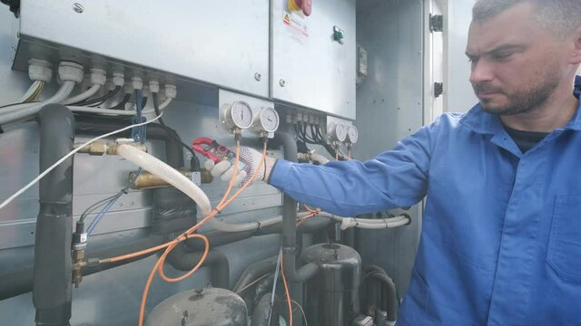 The technician checking power lines of the heat exchanger with current clamps