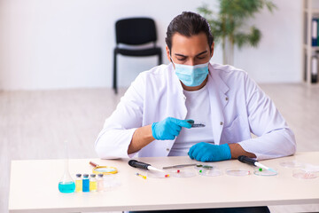 Young male chemist working in the lab during pandemic