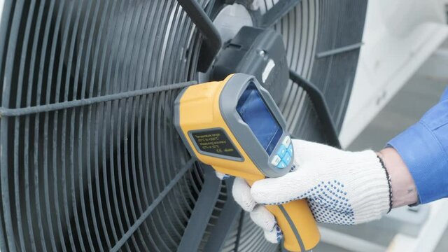 Technician uses a thermal imaging infrared thermometer to check the condensing unit heat exchanger