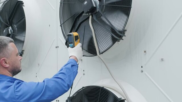 Technician uses a thermal imaging infrared thermometer to check the condensing unit heat exchanger