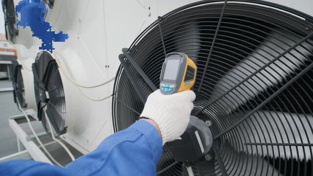 Technician uses a thermal imaging infrared thermometer to check the condensing unit heat exchanger