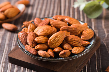 Delicious roasted sweet almonds nuts on wood background