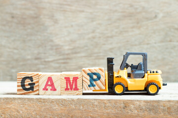 Toy forklift hold letter block p in word GAMP (Abbreviation of Good Automated Manufacturing...