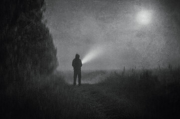 A moody atmospheric concept, of a spooky figure standing in a field with a torch on a foggy spooky...