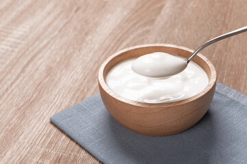 Obraz na płótnie Canvas Wooden bowl with yogurt on table