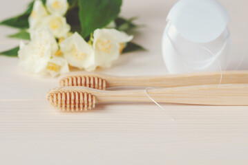 Two bamboo toothbrushes, dental floss and white flowers, closeup