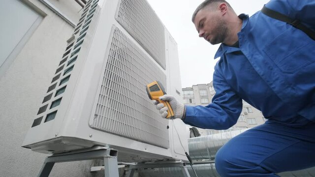 Technician uses a thermal imaging infrared thermometer to check the condensing unit heat exchanger