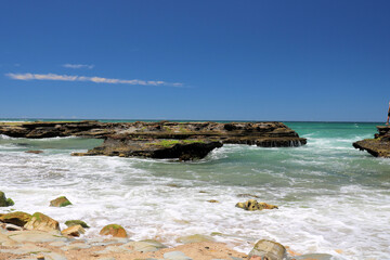Waves crashing onto the rocky shoreline at Dudley Beach New South Wales Australia