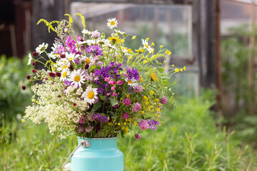Bouquet of bright wild flowers in tin can vase on table outdoors, rural scene. Template for postcard. Concept Womens day, Mothers Day, Hello summer or Hello spring