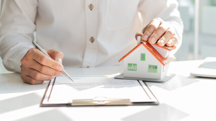 Real estate agents are working on paperwork and house plans on the table to offer purchase and lease agreements with financing.