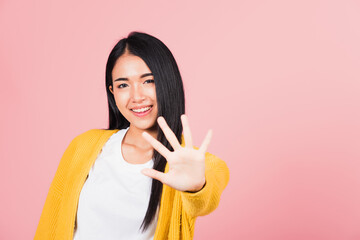 Asian portrait beautiful cute young woman teen smiling doing show stop sign gesture with palm of hand but happy face studio shot isolated on pink background, female doubt with copy space