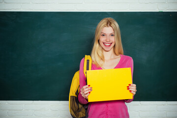 Student girl holding empty faper for product. Learn with fun. Funny female teacher sitting at her workplace and teaching English. Education concept.