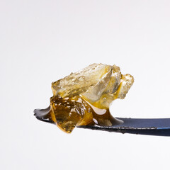 Close up of some live resin diamonds with a white background sitting on a titanium dab tool. 
