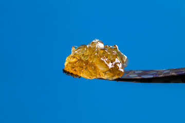 Honey Banan live resin diamond sitting gently on a leopard spotted titanium dab tool. 