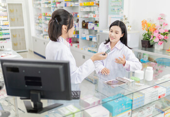 two asian pharmacists talk about drug information in drugstores, they exchange knowledge and...