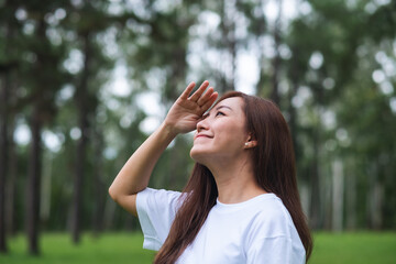 Portrait image of a young asian woman standing and looking at a beautiful nature in the park