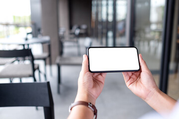 Mockup image of a woman holding mobile phone with blank white desktop screen