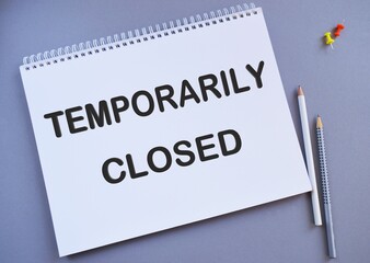 Temporarily Closed text written on a notebook with pencils, business concept