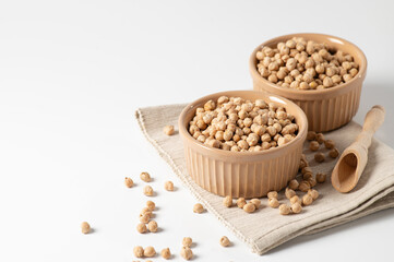 dry chickpeas, in a ceramic bowl on a white table, empty space for text